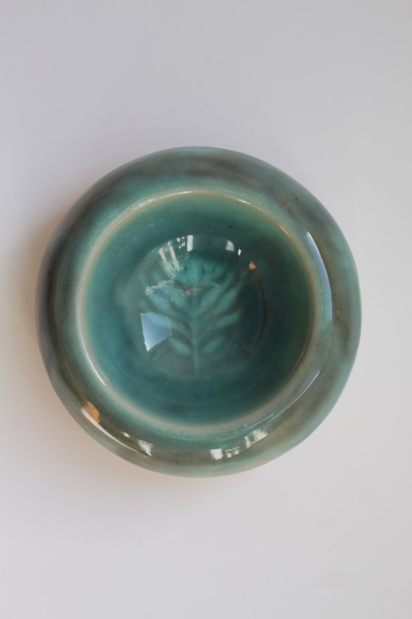 Green ceramic bowl with leaf design on a white background