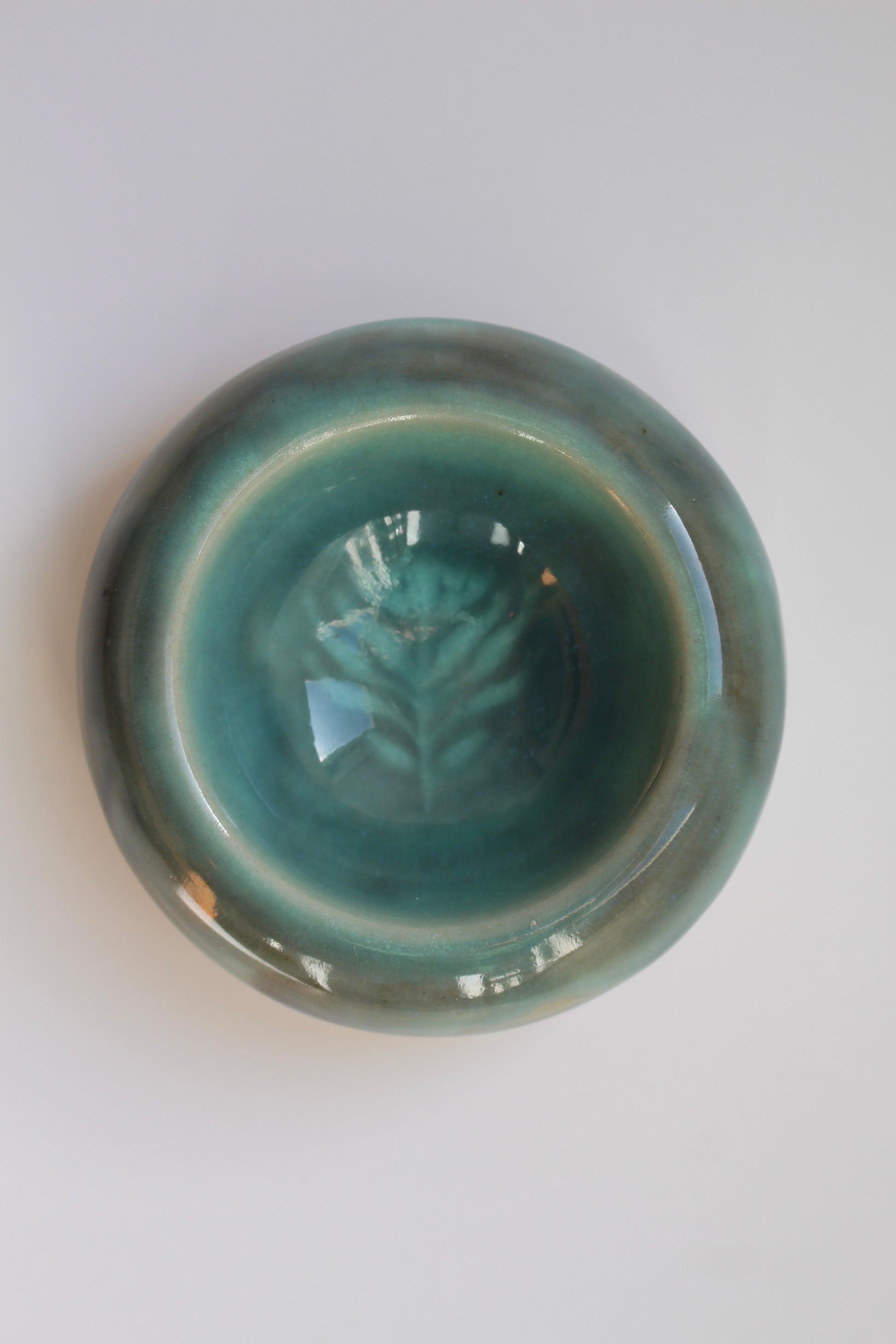 Green ceramic bowl with leaf design on a white background